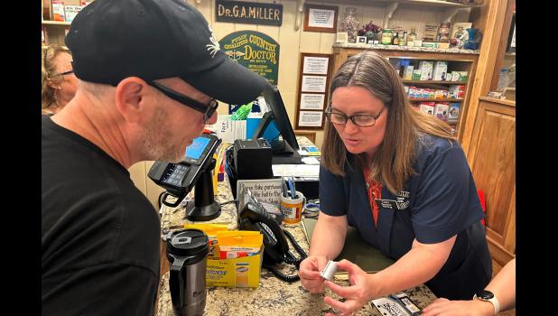 Pharmacist Cindy Dinger checks out tourist Will Lovitt after giving him advice on treating a mysterious rash he developed while visiting the Black Hills of South Dakota. Courtesy Arielle Zionts/KFF Health News