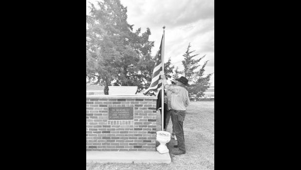 Sam Seymour takes down a flag from the memorial. Photo by Mishayla Buchannan